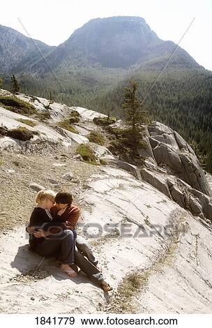 Stock Photo - Couple sitting on the edge in Jasper, Alberta, Canada. Fotosearch