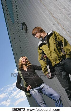 Stock Image - Couple walking together; Low angle view of teenage couple outdoors. Fotosearch