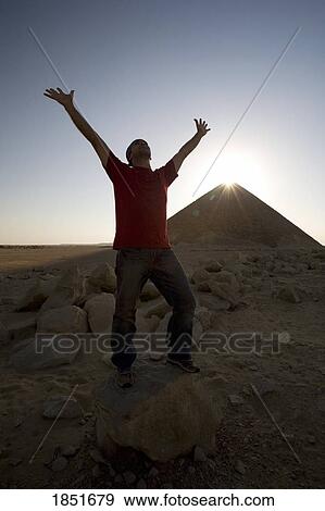 Stock Photo - Dahshur, Egypt; Man with arms raised in front of the Red Pyramid. Fotosearch