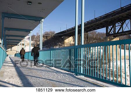 Stock Photo - Edmonton, Alberta, Canada; People walking on a foot bridge. Fotosearch
