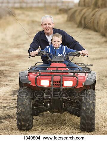 Picture - Father and son; Man and his son riding an all terrain vehicle. Fotosearch