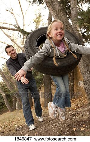 Stock Photo - Father pushing daughter on tire swing. Fotosearch