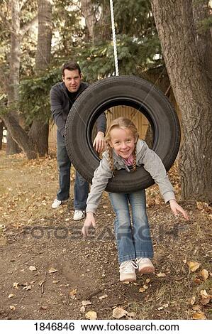 Stock Photograph - Father pushing daughter on tire swing. Fotosearch