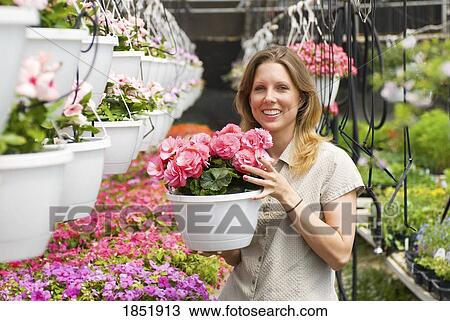 Stock Image - Flower shop; Woman holding flower pot. Fotosearch