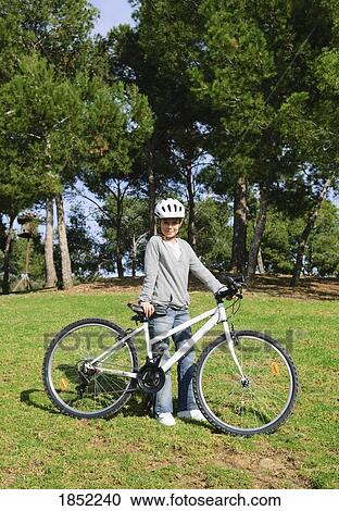 Stock Image - Girl with bike; Child standing beside bicycle. Fotosearch