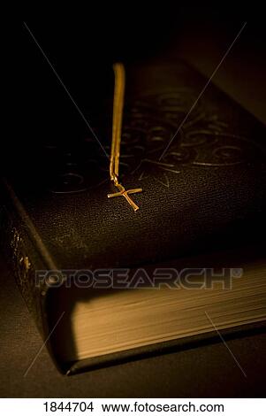 Gold cross pendant resting on a book View Large Photo Image Picture - Gold cross pendant resting on a book. Fotosearch