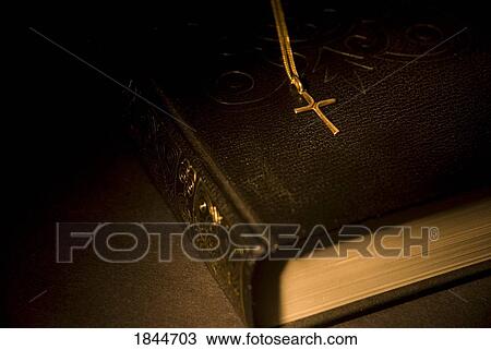 Gold cross pendant resting on a book View Large Photo Image Stock Image - Gold cross pendant resting on a book. Fotosearch