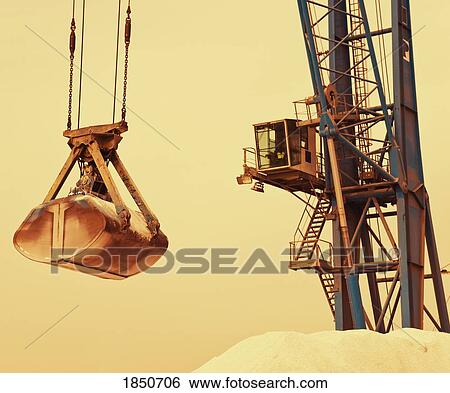 Stock Photograph - Harbour crane lifting phosphates in Malaga port, Spain; Crane lifting phosphates . Fotosearch