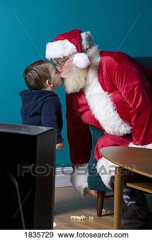 Stock Photo - Kisses from Santa for a little boy. Fotosearch