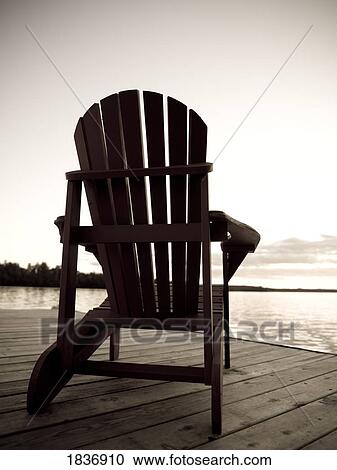 Stock Image - Lake of the Woods, Ontario, Canada; Adirondack chair on a dock. Fotosearch