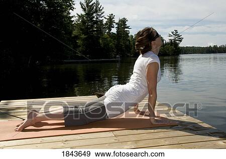 Stock Photo - Lake of the Woods, Ontario, Canada; Woman stretching on the dock. Fotosearch