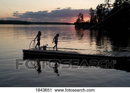 Stock Image - Lake of the woods, Ontario, Canada; Two girls on a dock. Fotosearch