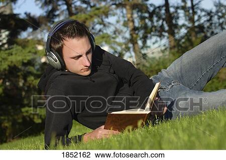 Stock Image - Listening to music and reading a book. Fotosearch