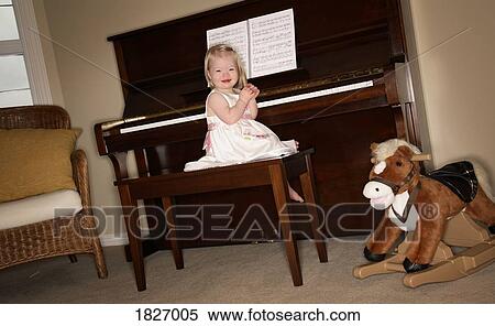 Stock Photography - Little girl sitting on piano bench. Fotosearch