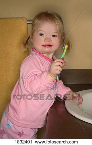 Stock Image - Little Girl Trying To Brush Her Teeth. Fotosearch