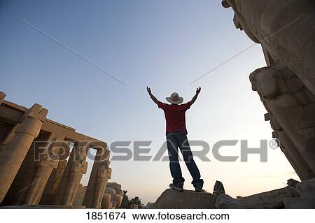Picture - Luxor, Egypt; Man with hat with raised arms visiting the Ramesseum. Fotosearch