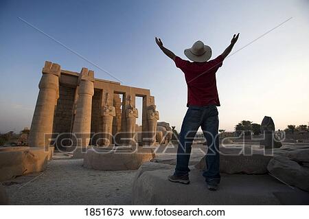 Stock Image - Luxor, Egypt; The Ramesseum, Man with his arms raised. Fotosearch