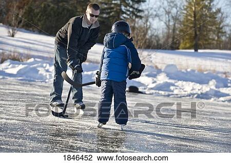 Stock Image - Man and child; man and child playing hockey. Fotosearch