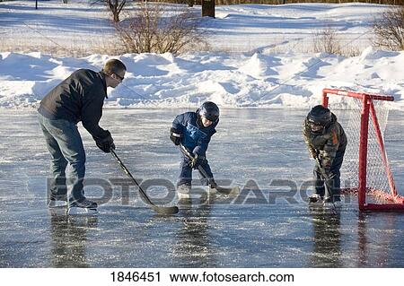 Stock Image - Man and two children playing hockey. Fotosearch