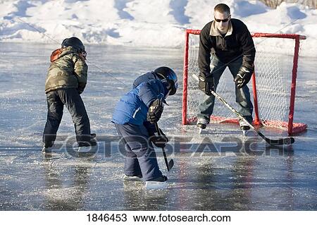 Stock Image - Man and two children playing hockey. Fotosearch