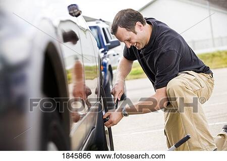 Man changing a tire View Large Photo Image Stock Photograph - Man changing a tire. Fotosearch