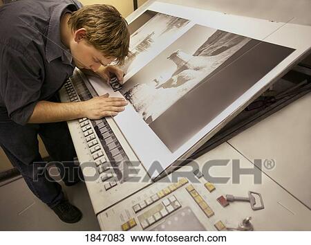 Stock Image - Man inspecting pictures. Fotosearch
