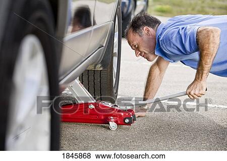 Man jacking up a vehicle View Large Photo Image Stock Photo - Man jacking up a vehicle. Fotosearch