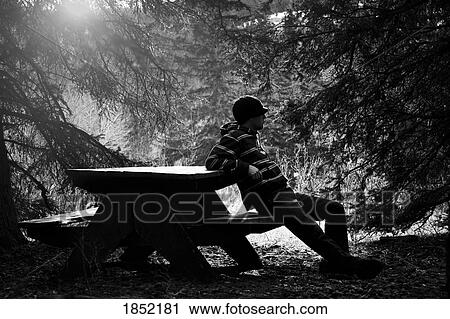 Stock Image - Man sitting; Man resting on picnic table. Fotosearch