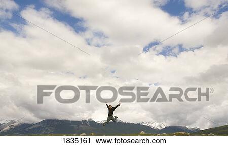 Person leaping on top of a mountain View Large Photo Image Stock Image - Person leaping on top of a mountain. Fotosearch