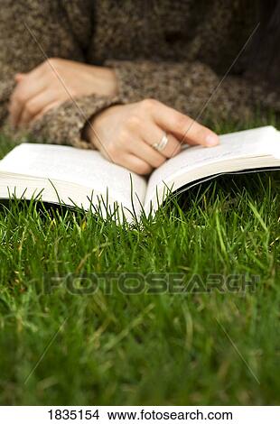 Person reading a book on the grass View Large Photo Image Picture - Person reading a book on the grass. Fotosearch