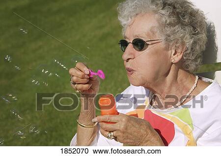 Playful senior; Senior woman blowing bubbles View Large Photo Image Stock Image - Playful senior; Senior woman blowing bubbles. Fotosearch