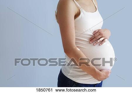 Stock Image - Pregnancy; Pregnant woman holding her belly. Fotosearch