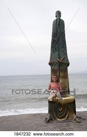 Stock Image - Puerto Vallarta, Mexico; Girl sitting by a statue . Fotosearch