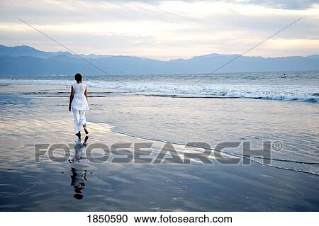 Stock Image - Puerto Vallarta, Mexico; Woman walking along the beach . Fotosearch
