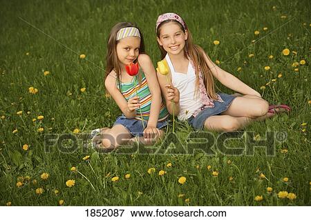 Relaxing outdooors; Portrait of two girls sitting in the grass View Large Photo Image Stock Photo - Relaxing outdooors; Portrait of two girls sitting in the grass. Fotosearch