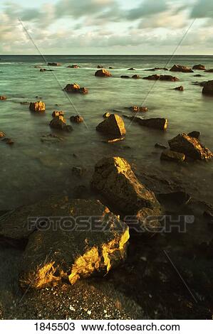 Rocks in shallow water by the shore View Large Photo Image Stock Image - Rocks in shallow water by the shore. Fotosearch