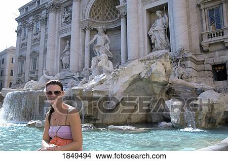 Picture - Rome, Italy; Woman sitting on the edge of the Trevi fountain. Fotosearch