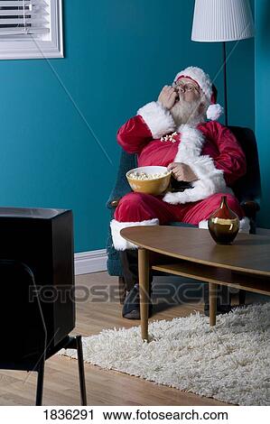 Stock Image - Santa sitting and eating popcorn. Fotosearch