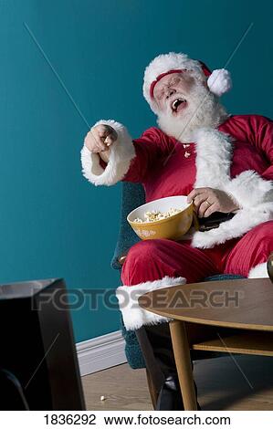 Stock Image - Santa sitting and eating popcorn. Fotosearch