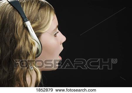 Stock Photo - Singer; Young girl singing with headphones on. Fotosearch