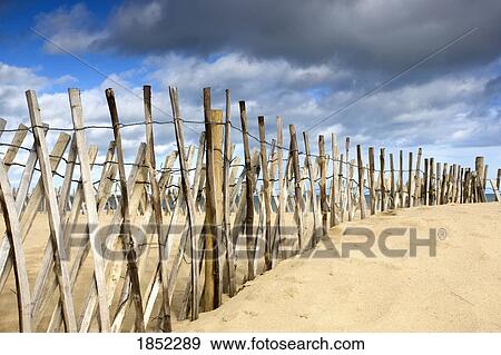Stock Photo - South Shields, Tyne and Wear, England; Dark clouds over fence on a beach. Fotosearch
