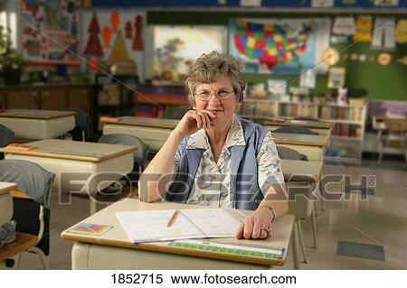 Stock Photography - Teacher; Teacher sitting at a desk in the classroom. Fotosearch