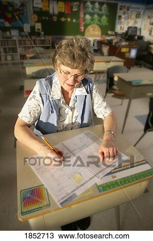 Stock Image - Teacher; Teacher sitting at a desk. Fotosearch