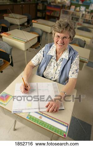 Stock Photograph - Teacher; Teacher sitting at school desk. Fotosearch