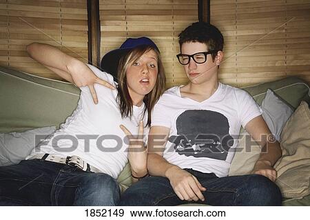 Stock Photo - Teenage boy and teenage girl; Teenagers sitting together on a couch. Fotosearch