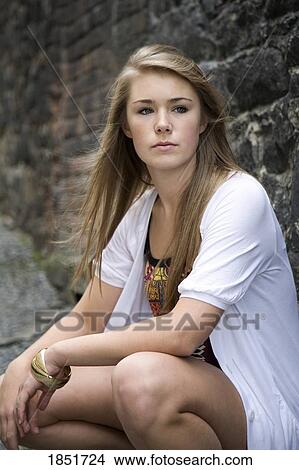 Picture - Teenage girl; teenage girl next to a stone wall. Fotosearch