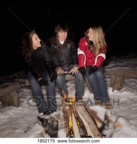 Stock Photography - Teenagers sitting by a fire. Fotosearch