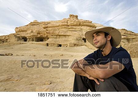 Stock Image - The 13th century mud-brick fortress of Shali, Siwa Town, Siwa Oasis, Egypt; male tourist sitting near fortress of Shali. Fotosearch