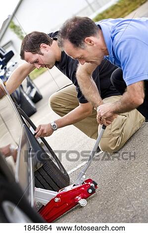 Two men fixing a flat tire View Large Photo Image Picture - Two men fixing a flat tire. Fotosearch