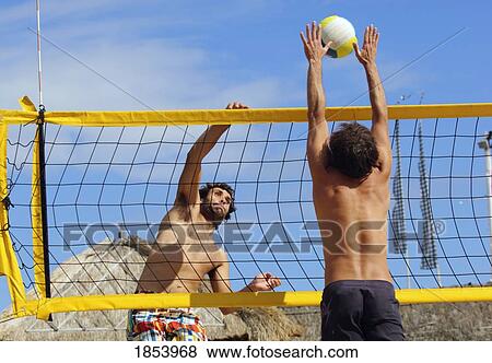 Stock Photo - Two men playing beach volleyball. Fotosearch